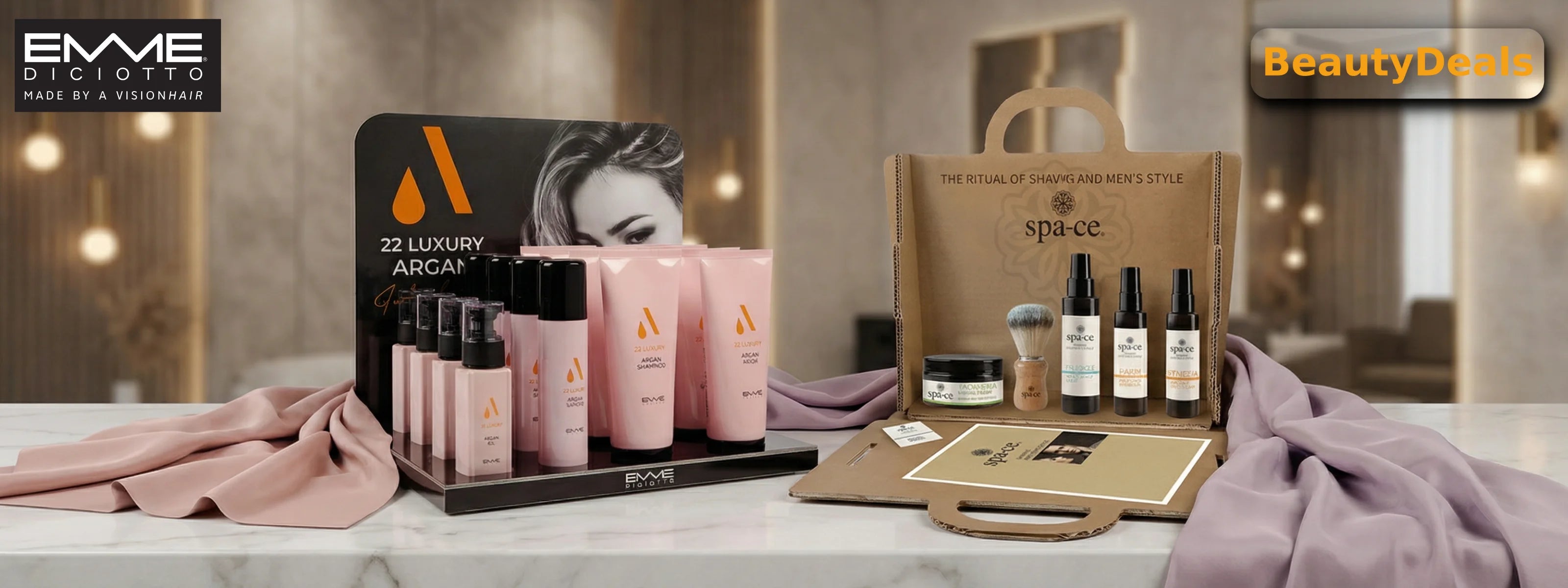 A luxurious display of Emme Diciotto pink argan oil shampoos, conditioners, and serums arranged on a draped silk cloth in a high-end salon. The scene includes professional silver round brushes and white branded boxes on a marble countertop.